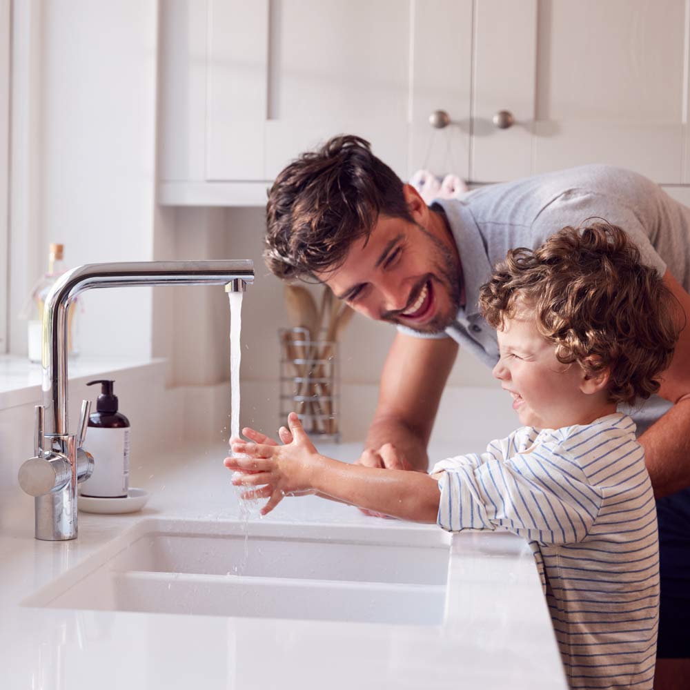 padre-che-aiuta-suo-figlio-lavarsi-le-mani-con-il-sapone-casa-per-fermare-la-diffusione-dell-infezione-nella-pandemia-sanitaria Padre con figli che insegna a lavarsi le mani in maniera allegra: Impianti idraulici Sassari: Energeo Srl